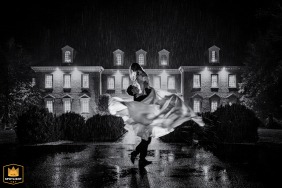 A beautiful black and white image of a groom spinning his bride in the rain on their wedding day at The Estate at River Run in Maidens, VA. The couple shares a romantic and tender dance together under the falling raindrops.
